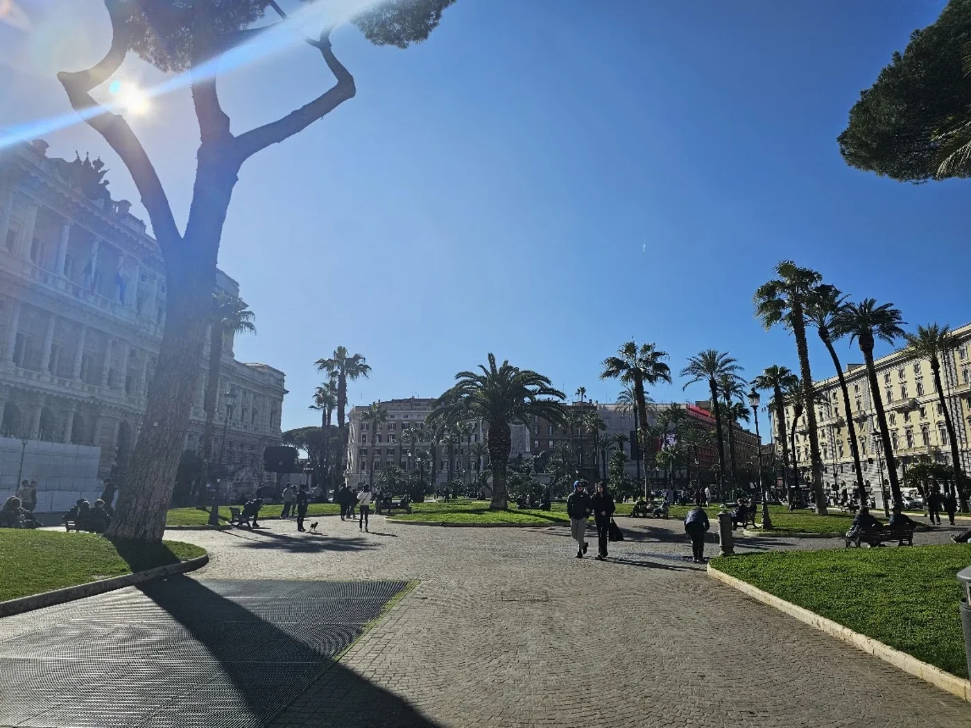 Il giardino di Piazza Cavour a Prati, con il Palazzo di Giustizia sullo sfondo e persone a passeggio