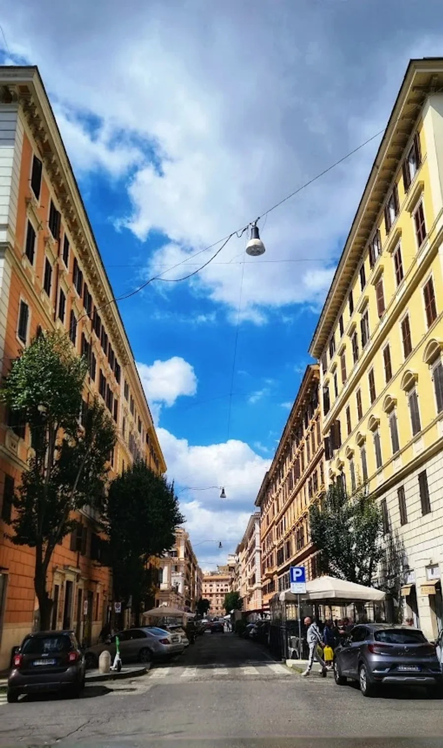 Una strada di Prati fiancheggiata da palazzi color pastello, vista dal centro della carreggiata